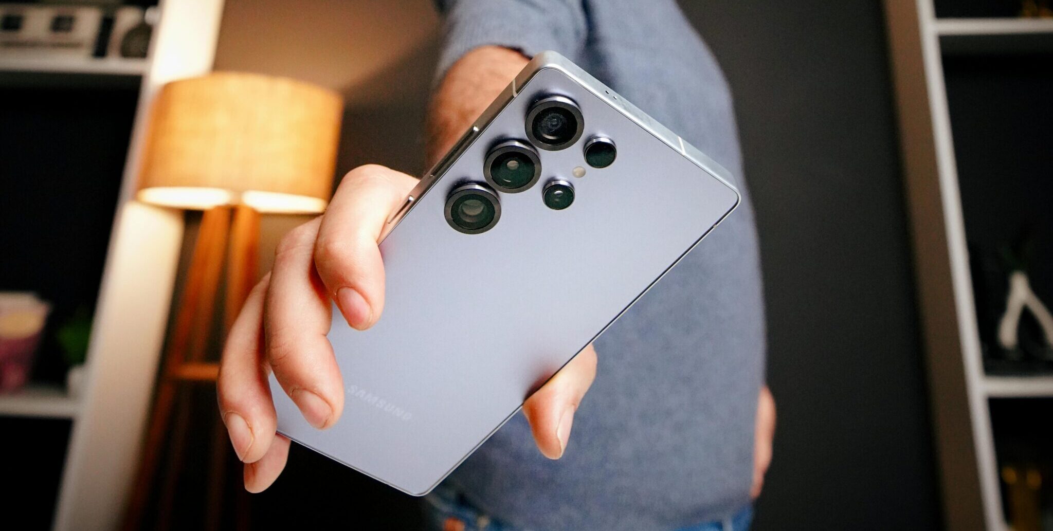 A man extends a sleek smartphone in a stylish office setting. Dynamic and modern focus.